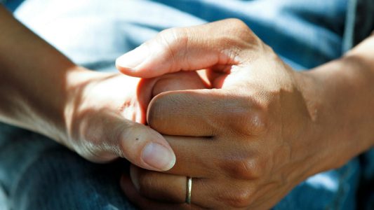 Two hands holding each other in support