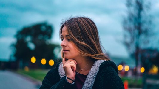Woman outdoors at dusk, thinking quietly