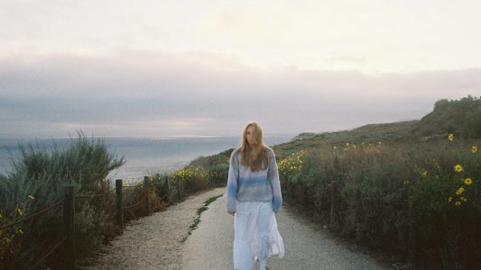 Woman walking alone on a coastal path at sunset
